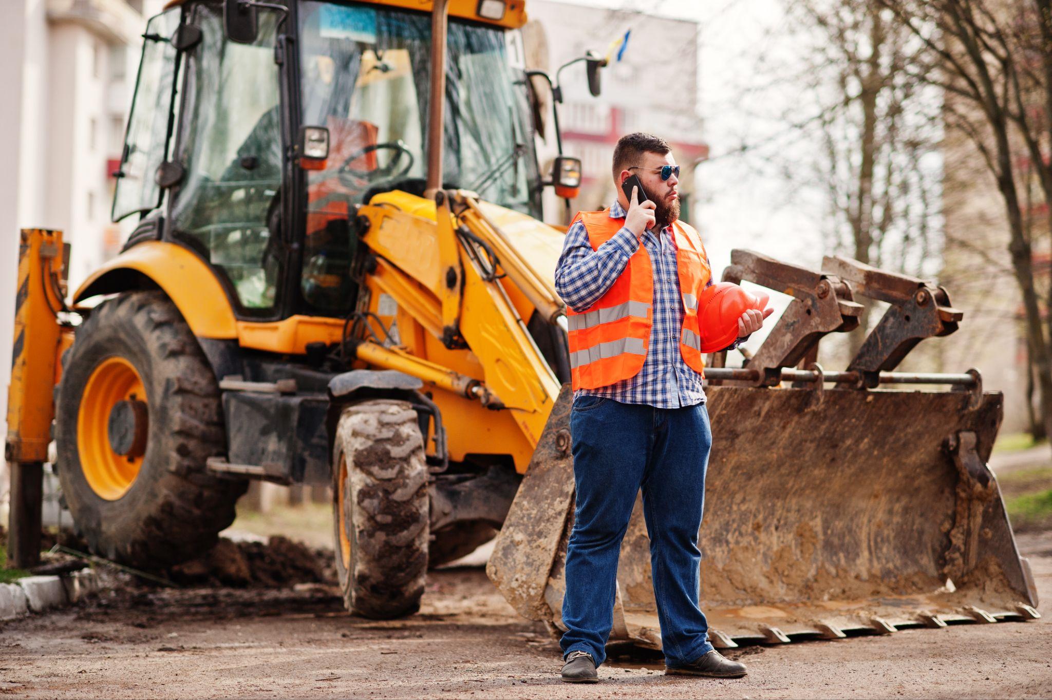 Demolition contractor coordinating heavy equipment on a residential construction site during full demolition work